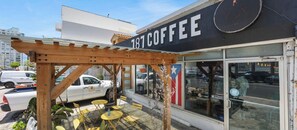 Een coffeeshop met terras, een houten pergola en een groot bord waarop het cijfer 181 staat.