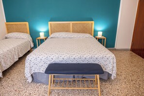 A bedroom with a bed, two bedside tables, a bench, and a wall with a blue hue. - Marina: 90 m² with a terrace, 200 m from the sea – up to 6 guests (Marina di Grosseto)