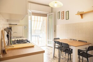 Ett modernt kök med en gasspis, ett matbord med stolar och en hängande lampa.