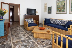 Una sala de estar con un sofá, dos sillones, una mesa de centro y un televisor.