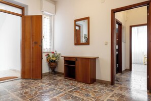A hallway with a wooden door, a mirror, a wooden console table, and a potted plant. - Marina: 90 m² with a terrace, 200 m from the sea – up to 6 guests (Marina di Grosseto)
