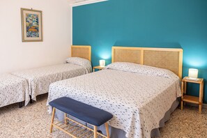 Una habitación con dos camas, un banco y un cuadro colgado en la pared.