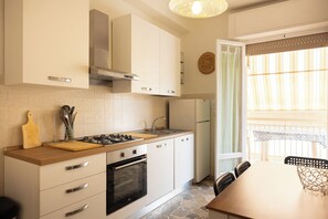 Una cocina moderna con estufa a gas, horno y comedor con mesa y sillas.