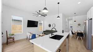 Cozinha moderna com ilha central, piso de madeira e iluminação pendente.