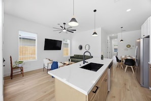 Una cucina moderna con isola centrale, pavimento in legno e illuminazione a sospensione.