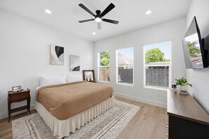 Una camera da letto con un letto, comodini, una ventola a soffitto, finestre e una TV.