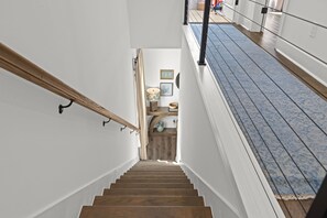Un escalier en bois mène à un palier d’où l’on a vue sur l’espace cuisine.