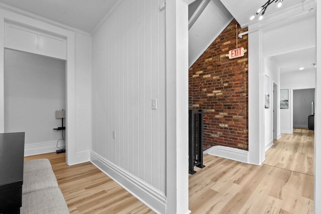 A modern interior with white walls, a wooden floor, and a brick accent wall.