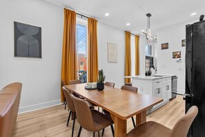 A modern kitchen with a black refrigerator, white cabinets, and a small island with a sink. - Hot Tub | 6BR-4BA | Sleep 12+ | Game Rm | Fire Pit (Louisville)