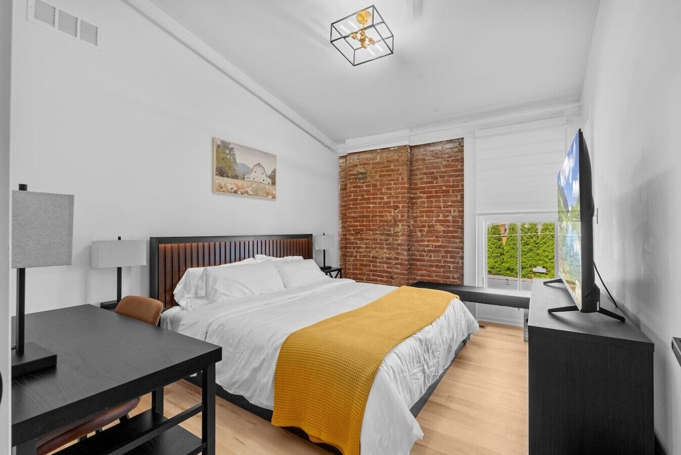 Ein modernes Schlafzimmer mit Bett, Nachttisch, Lampe und Fernseher.