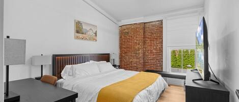 Ein modernes Schlafzimmer mit Bett, Nachttisch, Lampe und Fernseher.