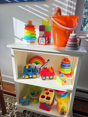 A toy shelf with various colorful toys, including a fire truck and a blue car. - Spacious 6-bedroom house with a pool, gameroom, office & plenty of free parking (Rehoboth Beach)