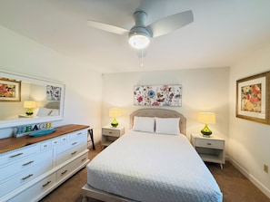 A bedroom with a bed, nightstands, a dresser, a ceiling fan, and wall art. - Spacious 6-bedroom house with a pool, gameroom, office & plenty of free parking (Rehoboth Beach)