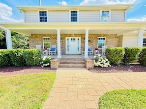 A two-story house with a front porch, a brick facade, and a white door. - Spacious 6-bedroom house with a pool, gameroom, office & plenty of free parking (Rehoboth Beach)