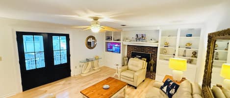 Una sala de estar con sofá, sillones, una mesa de centro, chimenea y televisor.