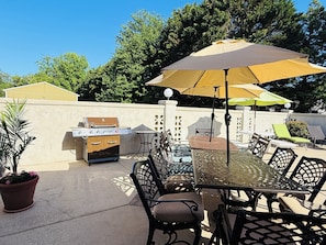An outdoor patio with a grill, dining table, chairs, and umbrellas. - Spacious 6-bedroom house with a pool, gameroom, office & plenty of free parking (Rehoboth Beach)