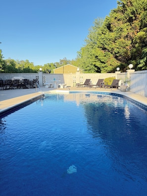 A swimming pool with lounge chairs and a building in the background. - Spacious 6-bedroom house with a pool, gameroom, office & plenty of free parking (Rehoboth Beach)