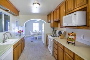 Una cocina con armarios de madera, microondas, estufa y lavaplatos.