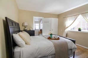 A bedroom with a bed, bedside table, lamp, and a window with curtains. - Spacious Room Prime Silicon valley (PALO ALTO)