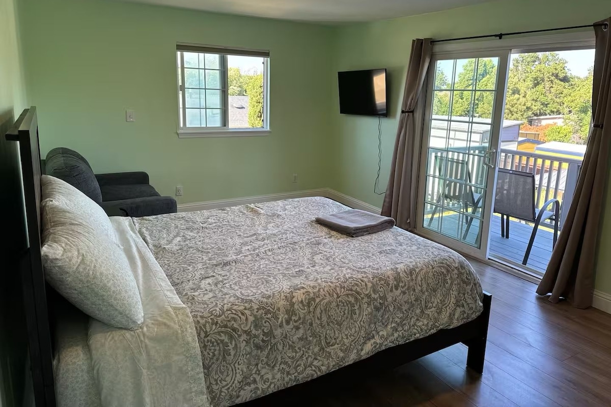 A bedroom with a bed, a TV, a window, and a balcony.