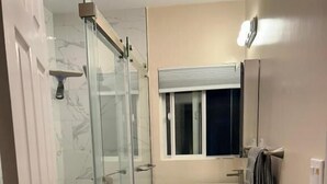 A bathroom with a glass shower enclosure, a sink, a mirror, and a window. - Spacious Room Prime Silicon valley (Palo Alto)