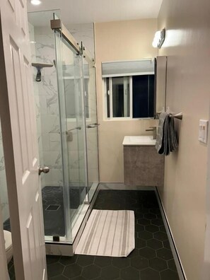 A bathroom with a glass shower enclosure, a sink, a mirror, and a window. - Spacious Room Prime Silicon valley (PALO ALTO)