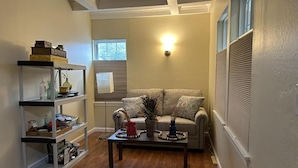 A living room with a sofa, a coffee table, and a bookshelf. - Spacious Room Prime Silicon valley (Palo Alto)