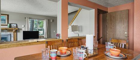 A dining area with a wooden table set for four, surrounded by chairs.