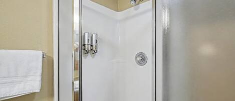 A bathroom with a glass shower door, a white towel hanging on the wall, and a toilet.