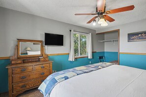 A bedroom with a bed, dresser, television, window, and ceiling fan. - Trapper 1 (West Yellowstone)