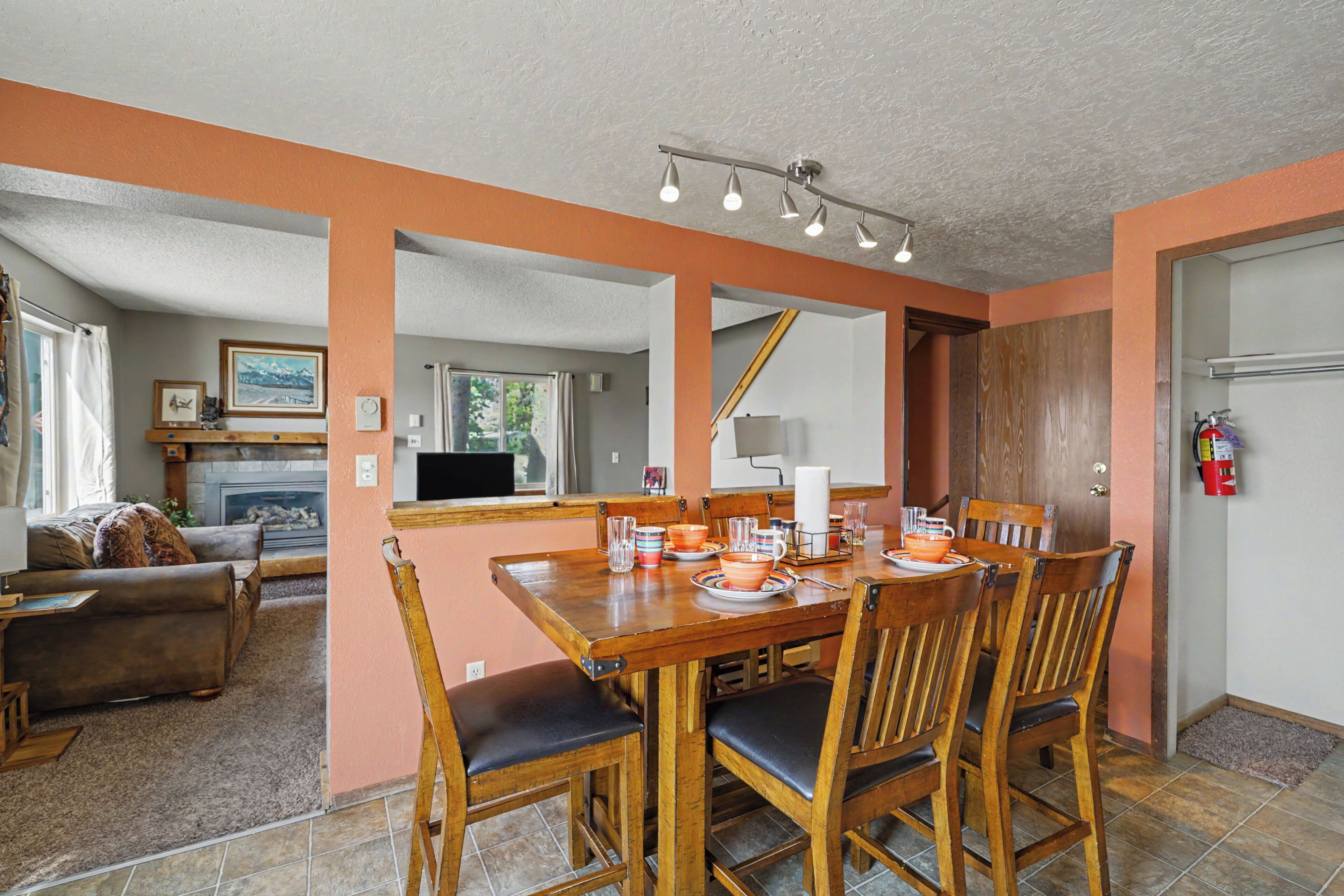 Un comedor con una mesa y sillas de madera, una chimenea y vista al salón.