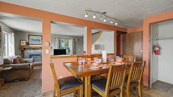 Un comedor con una mesa y sillas de madera, una chimenea y vista al salón.