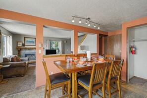 Un comedor con una mesa y sillas de madera, una chimenea y vista al salón.
