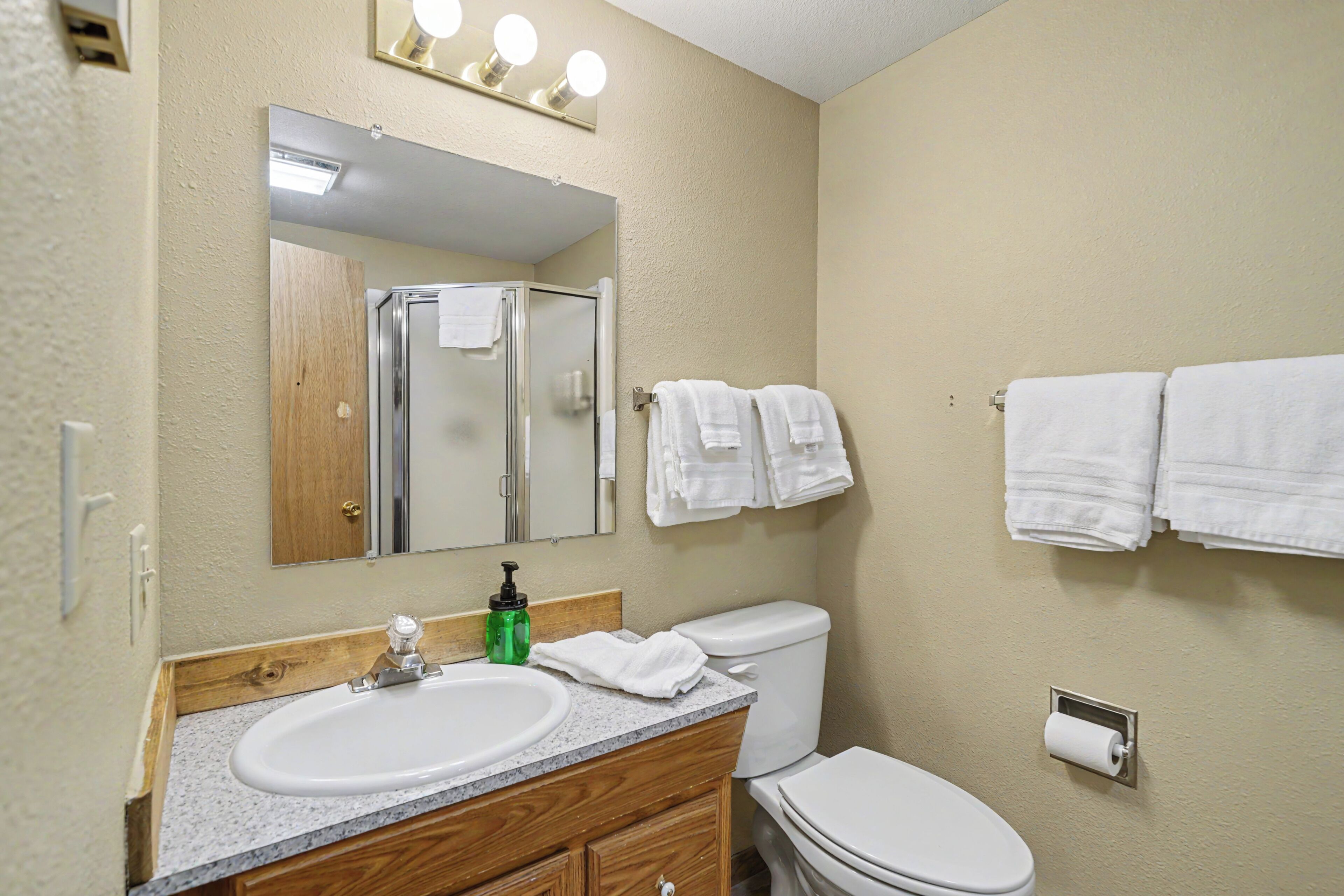 Une salle de bain équipée d’un lavabo, d’un miroir, de toilettes et d’un porte-serviettes.