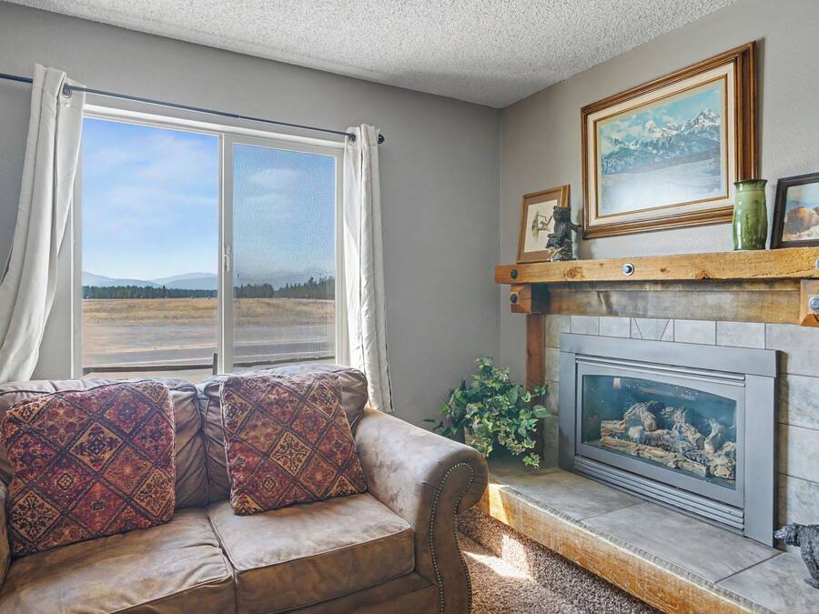 A living room with a sofa, a fireplace, and a window with curtains.