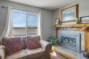 Una sala de estar con un sofá, chimenea y ventana con cortinas.