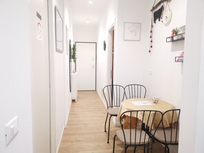 A hallway leading to a dining area with a table and chairs, a plant, and wall decorations. - KAIXIN'S HOUSE (Private garden + 15-minute bus ride to Venice) (Venezia)