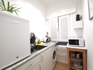 A compact kitchen with a washing machine, microwave, and a small coffee station. - KAIXIN'S HOUSE (Private garden + 15-minute bus ride to Venice) (Venezia)