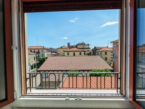 A balcony with a view of terracotta-roofed buildings, a metal railing, and a clear sky. - KAIXIN'S HOUSE (Private garden + 15-minute bus ride to Venice) (Venezia)