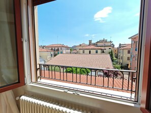 A window with a view of a residential area, a balcony with a metal railing, and a white radiator. - KAIXIN'S HOUSE (Private garden + 15-minute bus ride to Venice) (Venezia)