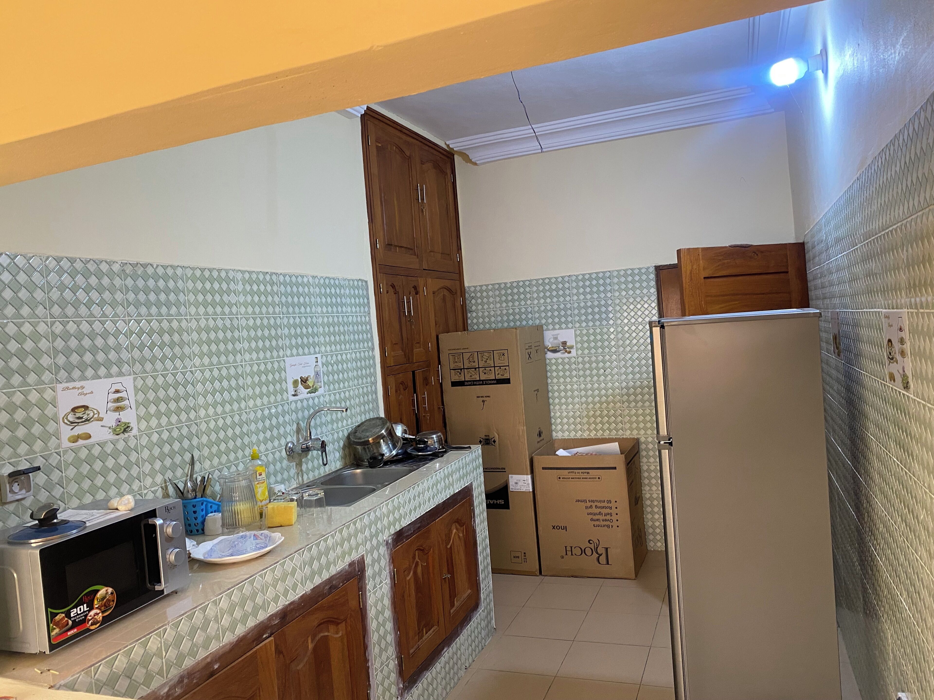 A kitchen with a microwave, sink, cabinets, and boxes, possibly for moving.