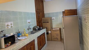 A kitchen with a microwave, sink, cabinets, and boxes, possibly for moving. - Seemingly luxurious & peaceful (Godomey)