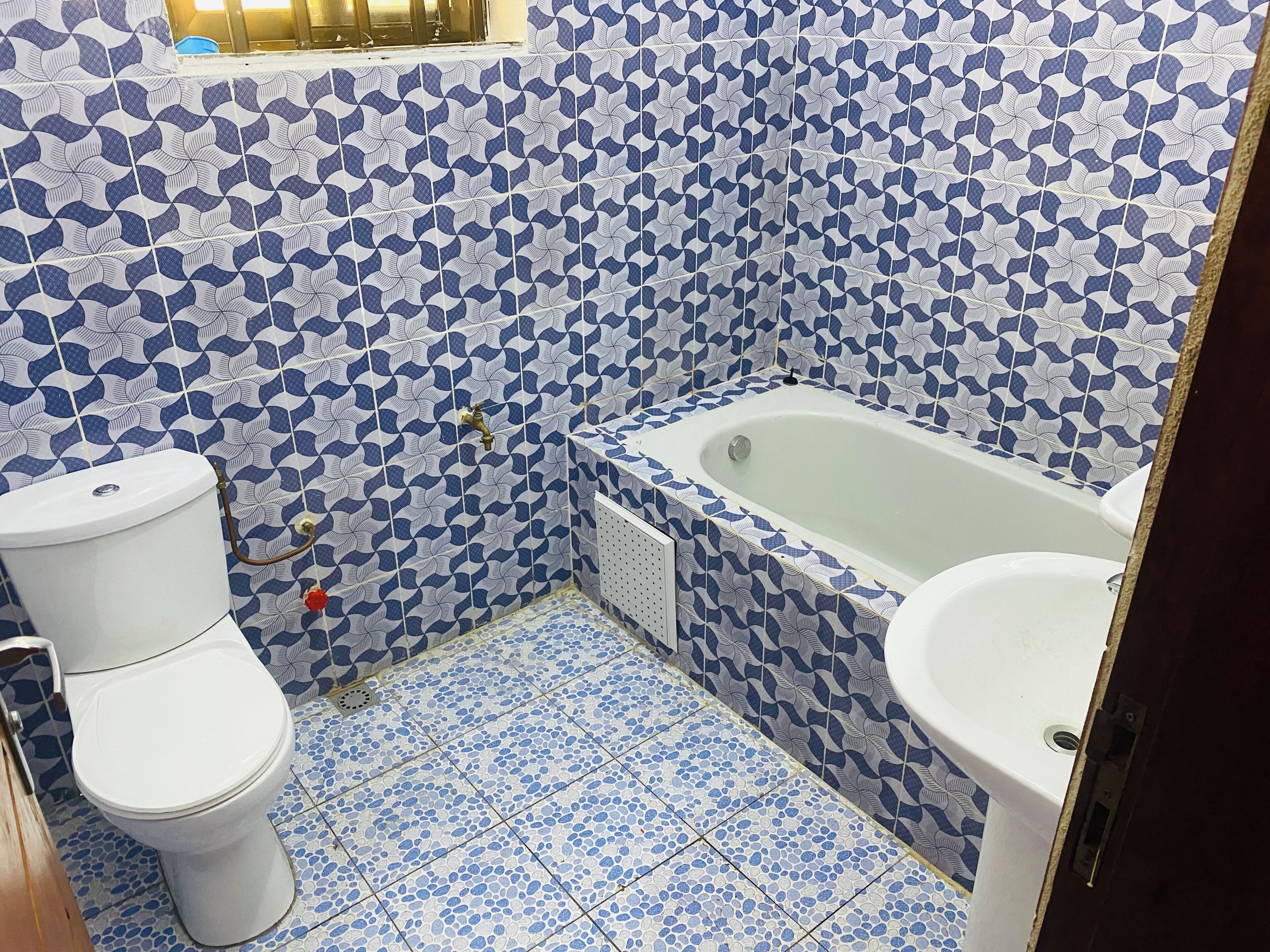 A bathroom with a toilet, bathtub, and sink, all with a blue and white patterned tile design.