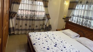 A hotel room with a bed, curtains, an air conditioning unit, and a nightstand. - Seemingly luxurious & peaceful (Godomey)