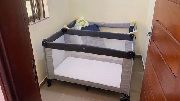 A room with a portable crib, a window, and a wooden door. - Seemingly luxurious & peaceful (Godomey)