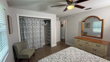 A bedroom with a bed, a chair, a dresser, a ceiling fan, and a walk-in closet.