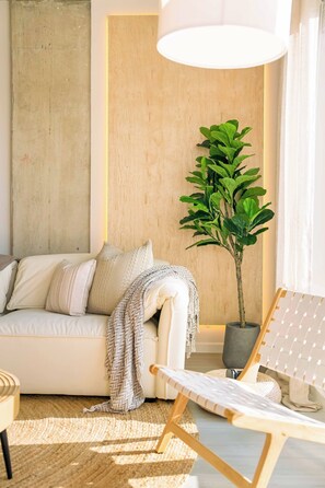 A modern living room with a sofa, a potted plant, a chair, and a large lamp. - The Emma - Luxury 1BR Condo King Bed, Pool, Gym (Orlando)