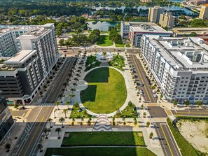 A high-rise building with a central courtyard surrounded by roads and greenery. - The Emma - Luxury 1BR Condo King Bed, Pool, Gym (Orlando)
