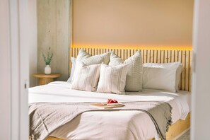 A bed with a wooden headboard, white bedding, and multiple pillows. - The Emma - Luxury 1BR Condo King Bed, Pool, Gym (Orlando)