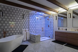 Uma casa de banho moderna com uma banheira independente, área de duche com paredes de vidro e toucador de madeira com espelho.